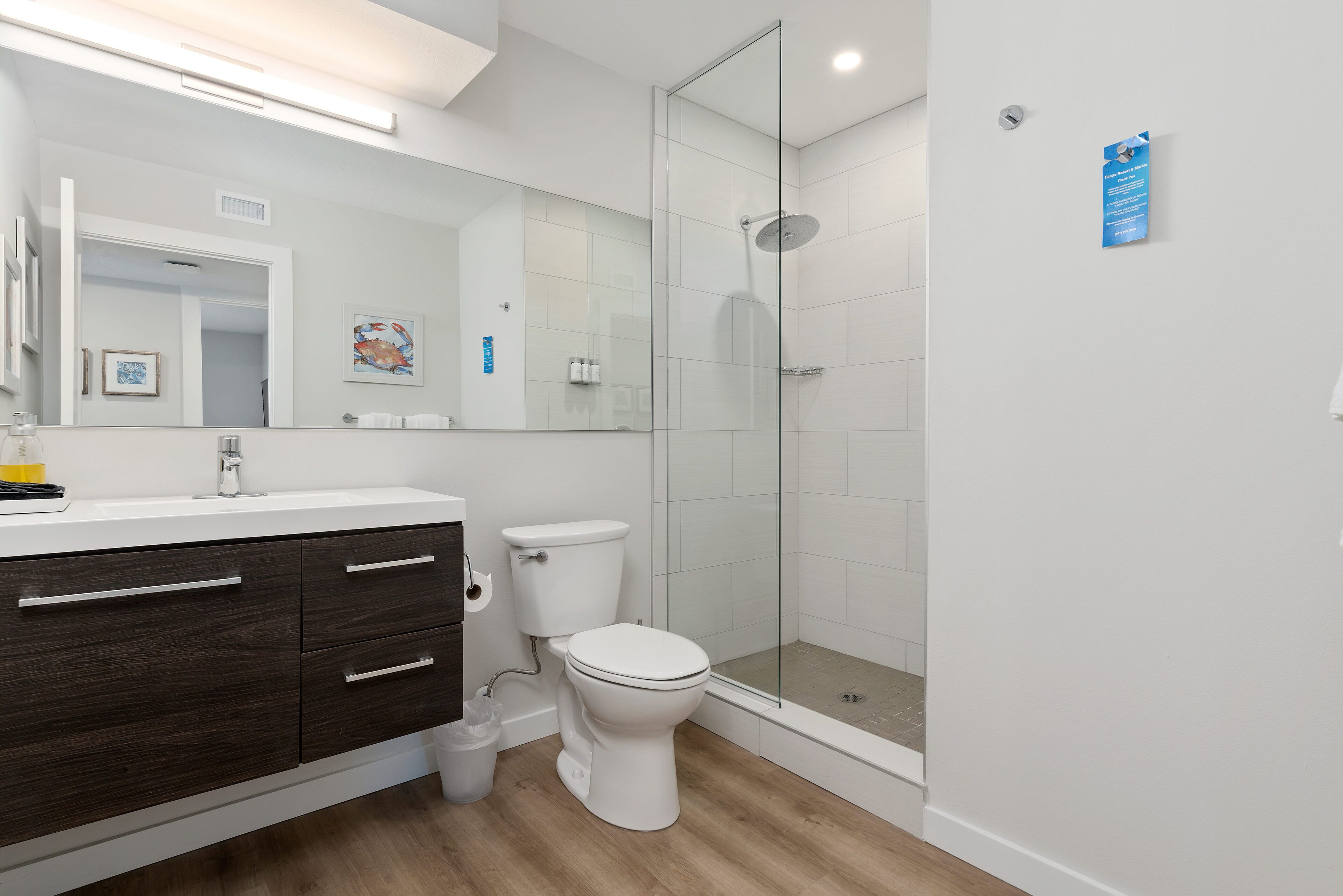 A modern bathroom with a glass-enclosed shower, a white toilet, and a dark wood vanity.