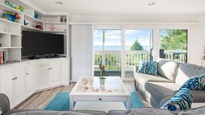 Un salon avec un téléviseur, des meubles blancs, un canapé et un balcon avec vue.