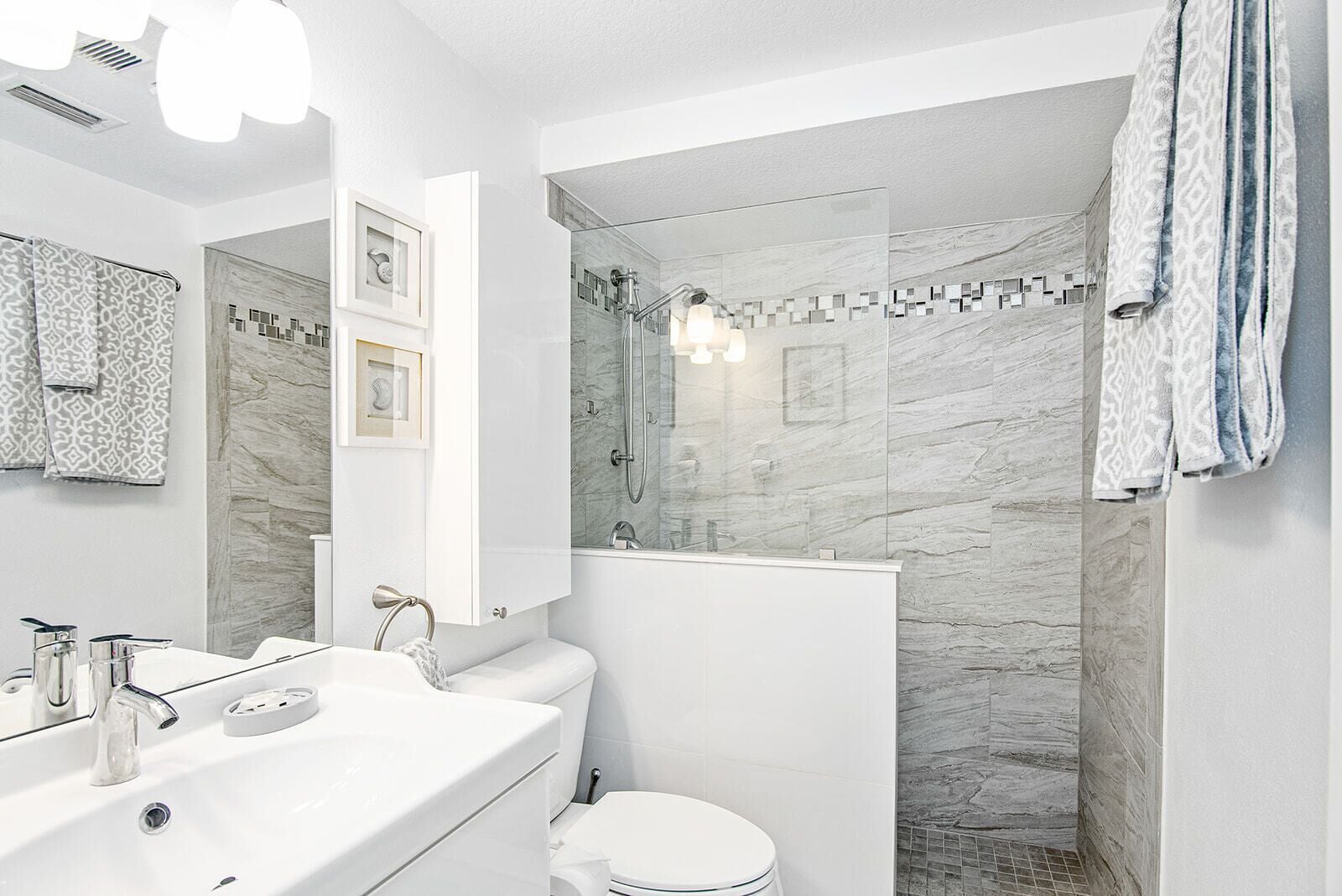 A modern bathroom with a shower, toilet, sink, and vanity.