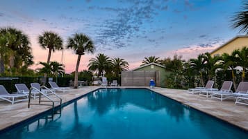 Una piscina al aire libre, sombrillas, sillones reclinables de piscina