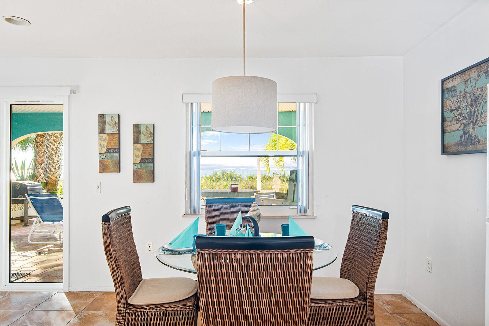 A dining area with wicker chairs, a table, and a pendant light.