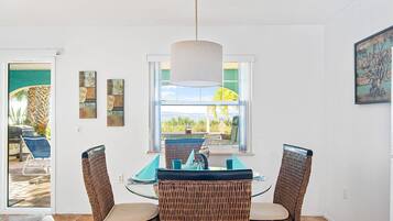 A dining area with wicker chairs, a table, and a pendant light.