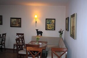 A dining area with a table, chairs, a sofa, and wall-mounted artwork. - Landhotel Garni Am Mv Hlenwv Rth (Tauberbischofsheim)