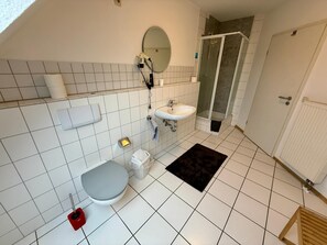 A bathroom with a toilet, sink, mirror, and shower. - Landhotel Garni Am Mv Hlenwv Rth (Tauberbischofsheim)