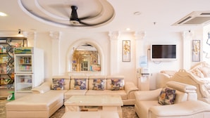 A spacious living room with a sectional sofa, a coffee machine, a TV, and a water dispenser. - C'Lavie Hotel - Saigon Airport Hotel (Ho Chi Minh City)