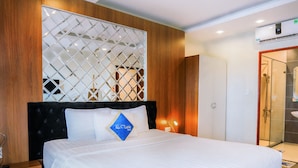 A modern hotel room with a large bed, wooden paneling, a decorative wall, and a visible bathroom with a glass shower. - C'Lavie Hotel - Saigon Airport Hotel (Ho Chi Minh City)