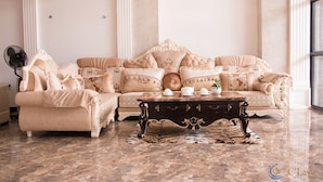 A luxurious living room with a beige sofa set, a dark wooden coffee table, and a fan. - C'Lavie Hotel - Saigon Airport Hotel (Ho Chi Minh City)