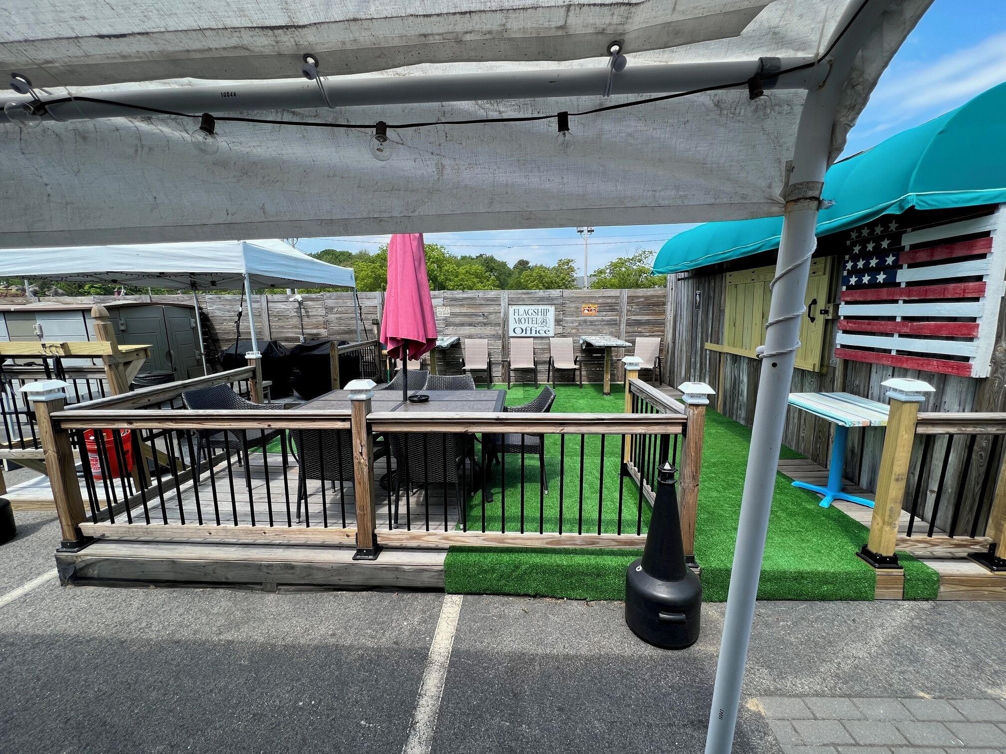 A patio area with a table and chairs, a grill, and a flag-themed wall.