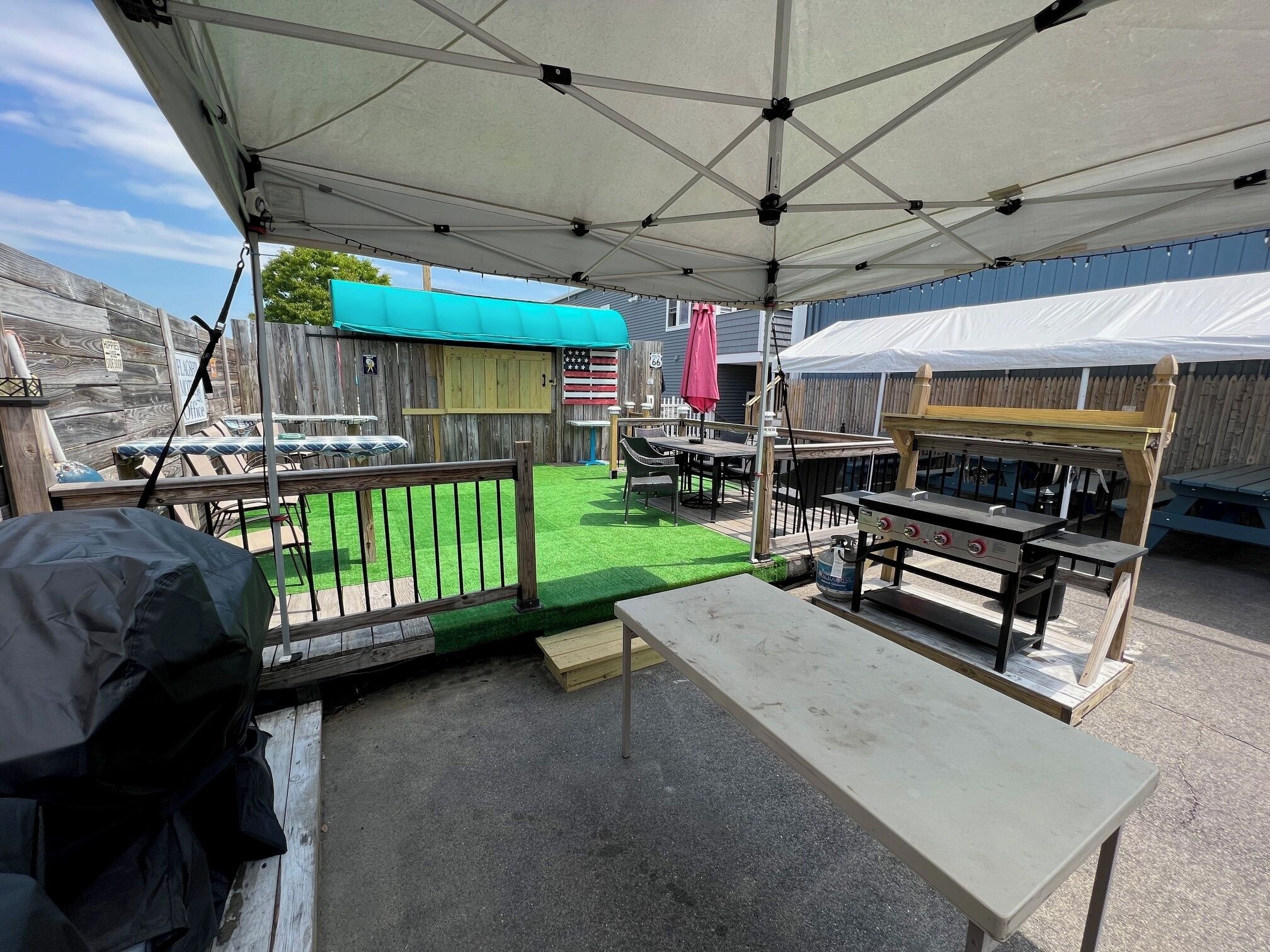 Ein Außenbereich mit Terrassenmöbeln, einem Grillplatz und einem umzäunten Spielbereich.