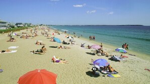 A crowded beach with people sunbathing and swimming, umbrellas, and beach chairs. - Seagrass Inn (Old Orchard Beach)