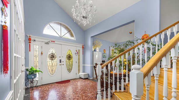 A spacious hallway with a wooden staircase, a chandelier, and a door with decorative glass panels. - Charming Family Hotel (Richmond)