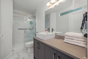 Bañera con ducha, pantuflas, toallas