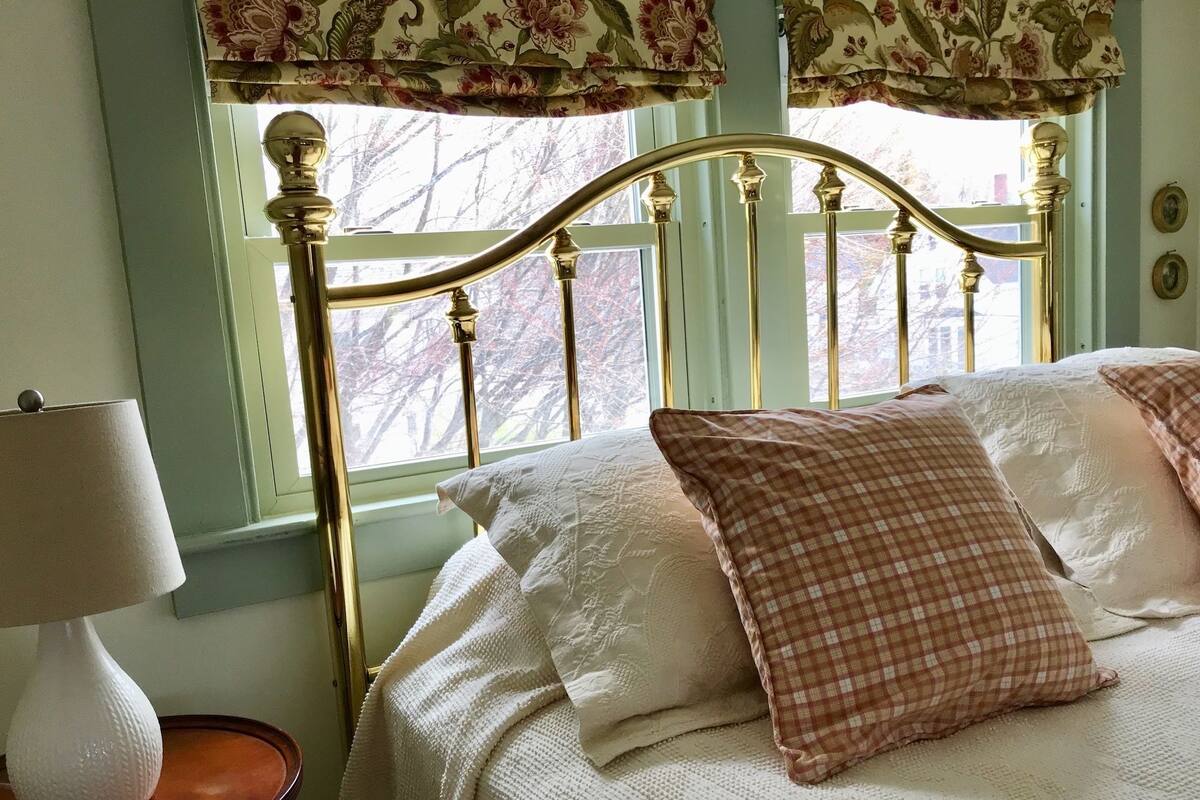 Ein Schlafzimmer mit einem Bett, einer Nachttischlampe und einem Fenster mit Vorhängen.
