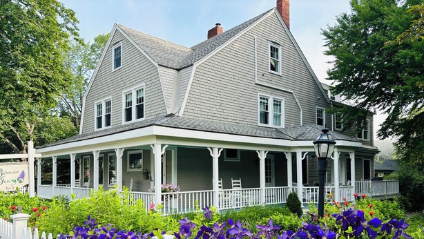 A large, two-story house with a porch and a garden in front. - The Belmont Inn (Camden)