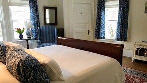 A neatly arranged bedroom with a large bed, a chair, a dresser, and a mirror. - The Belmont Inn (Camden)