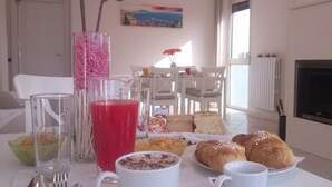 A breakfast setting with a table set for two, including croissants, muffins, and a glass of red juice. - B&B Zefiro (Pompei)