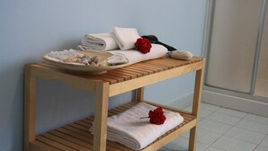 A wooden shelf with towels and a rose, and a bowl of snacks. - B&B Zefiro (Pompei)