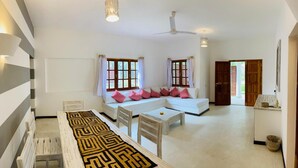 A spacious living area with a sofa set, a dining table, and a patterned rug.