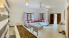 A spacious living area with a sofa set, a dining table, and a patterned rug.