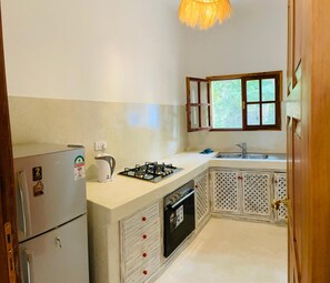 A compact kitchen with a refrigerator, stove, sink, and window.