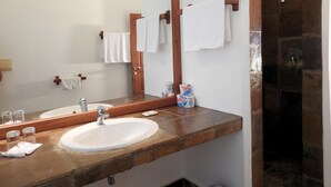 A bathroom with a wooden vanity, a large mirror, a sink, and a shower area.