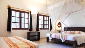 A bedroom with two beds, a nightstand, and a window with curtains.