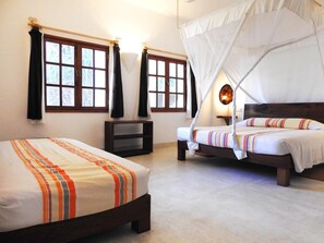 A bedroom with two beds, a nightstand, and a window with curtains.