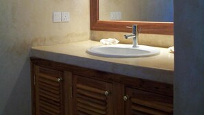 A bathroom with a wooden vanity, a white sink, and a mirror with a wooden frame.