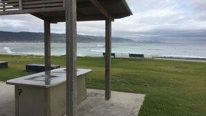 Een overdekt terras met uitzicht op de oceaan en verre bergen.