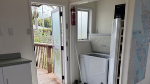 A kitchen with a refrigerator, a fire extinguisher, and a map on the wall. - Tokerau Beach Paradise (Tokerau Beach)