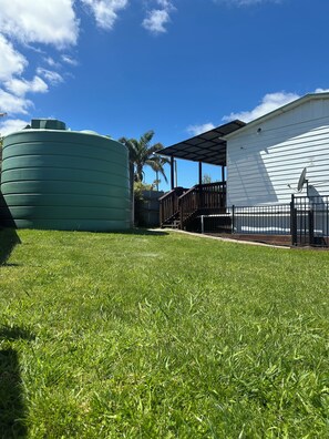 Un patio cubierto de césped con un depósito de agua y un edificio con porche techado.
