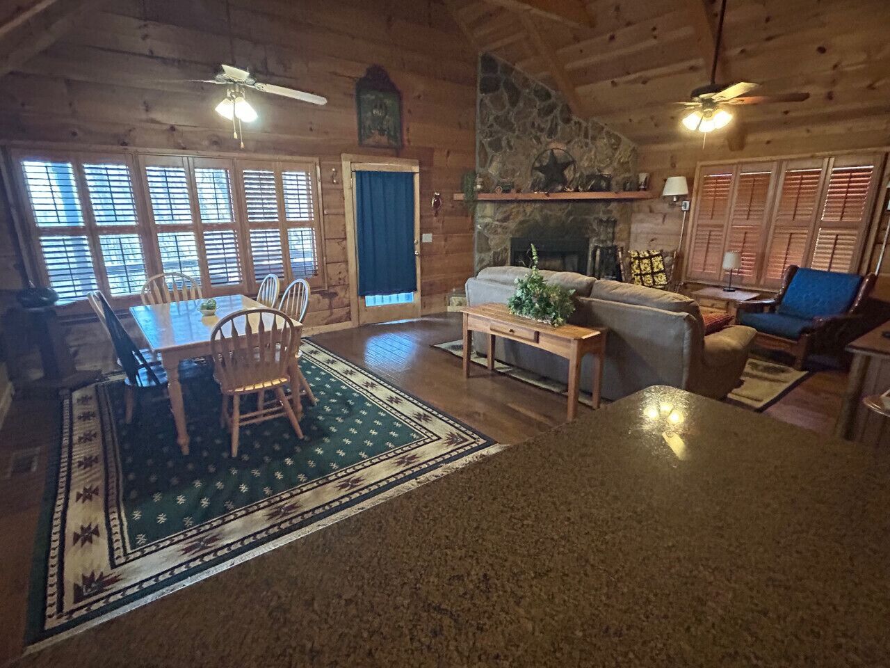 A log cabin interior with a dining area, a fireplace, and a stone wall.