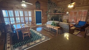 A log cabin interior with a dining area, a fireplace, and a stone wall. - Trail`s End-Hot tub-Wi-Fi,-pets ok-Pool Table-Fireplace-Screened Porch-Activities (Morganton)