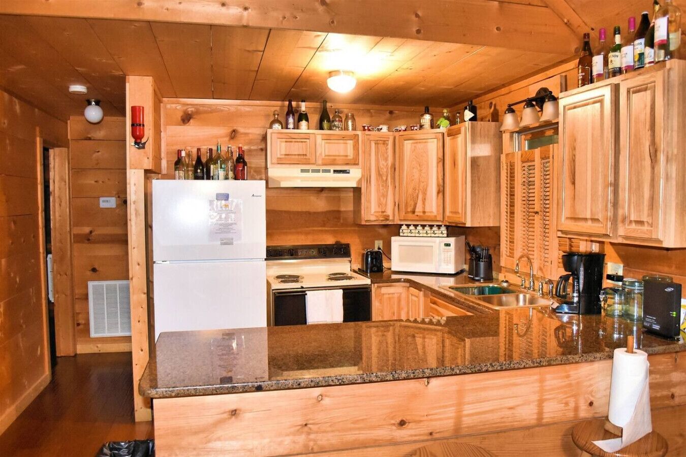 Une cuisine de taille réduite, dotée de meubles en bois, d’un réfrigérateur, d’une cuisinière, d’un four à micro-ondes et d’un évier.