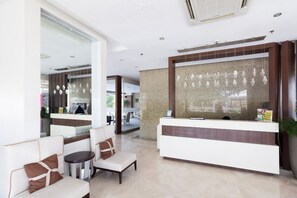 A modern reception area with a reception desk, seating area, and a large window with decorative hanging elements. - Luxury Condo 904 at The Padgett Place (Cebu City)