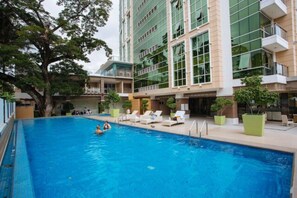 A swimming pool with lounge chairs and a building with large windows and balconies in the background. - Luxury Condo 904 at The Padgett Place (Cebu City)