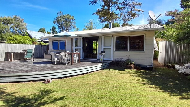 A house with a deck, a patio with chairs, and a satellite dish. - Quaint Lockwood River Cottage (Turangi)