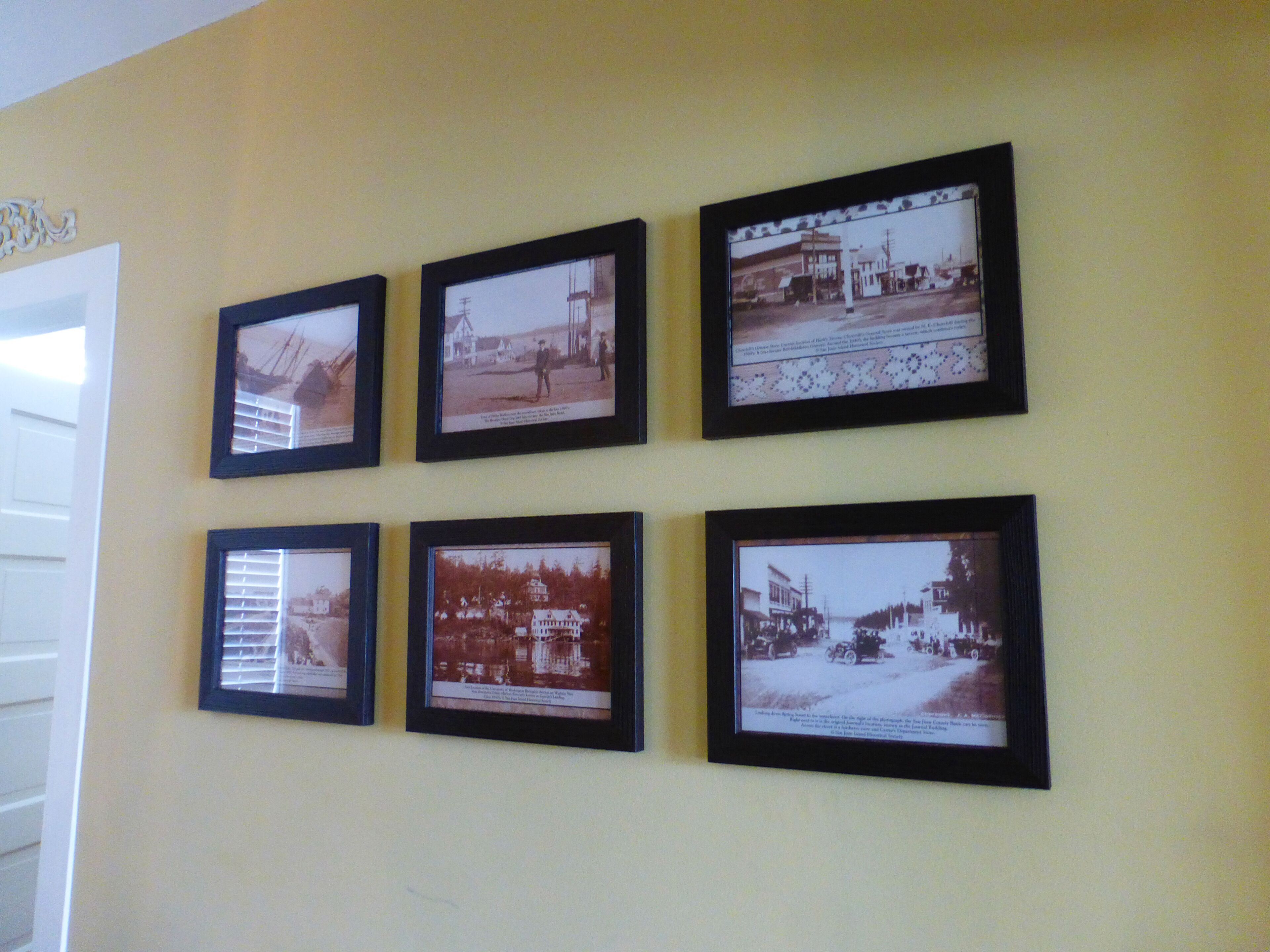 Sechs gerahmte historische Fotografien an einer Wand.