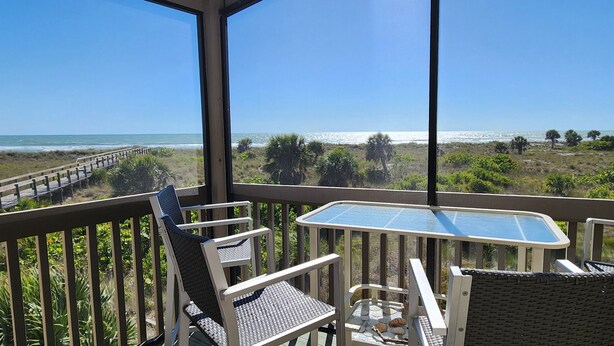 A balcony with a view of the beach, equipped with wicker chairs and a small table. - Beachfront - Romantic - Relaxing - Panoramic Views - Little Gasparilla Island  (Placida)
