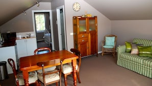 Un comedor con una mesa y sillas de madera, una silla de mimbre y un sofá verde a rayas con almohadones.
