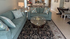 A living room with a sofa set, a coffee table, and a dining area with a table and chairs.