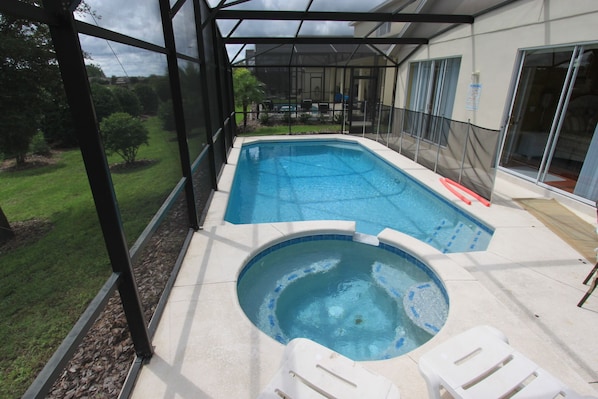 Een zwembad met een jacuzzi, omgeven door een overdekt terras met glazen balustrades.