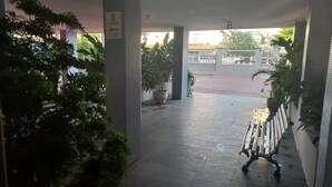 Un'area esterna riparata, con pavimento piastrellato, piante in vaso e una panchina.