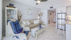 Ein Wohnzimmer mit Sofa, Sessel, Couchtisch und Deckenventilator.