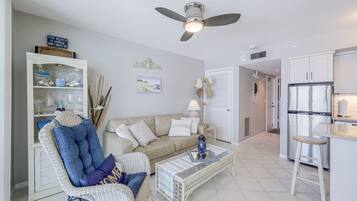 A living room with a sofa, armchair, coffee table, and a ceiling fan.