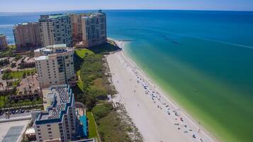 A coastal hotel with multiple high-rise buildings, a sandy beach, and a clear view of the ocean.