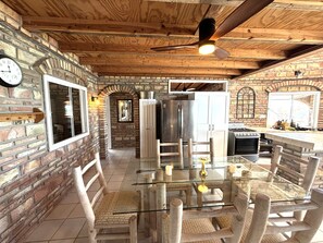 Una cocina rústica con pared de ladrillo, techo de madera y una mesa de comedor de vidrio.