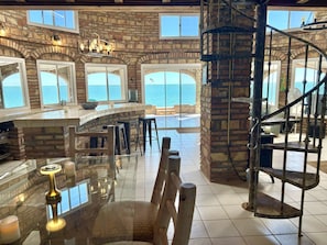 A spacious room with a stone wall, a curved bar area, and a spiral staircase.