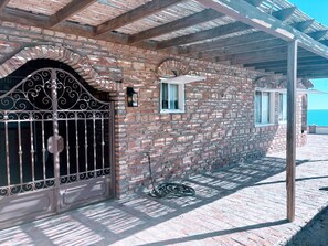 Edificio de ladrillo con una reja metálica, una ventana y una manguera en el suelo.