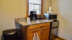 Una cocina compacta con encimera de granito, cafetera, microondas y refrigerador.